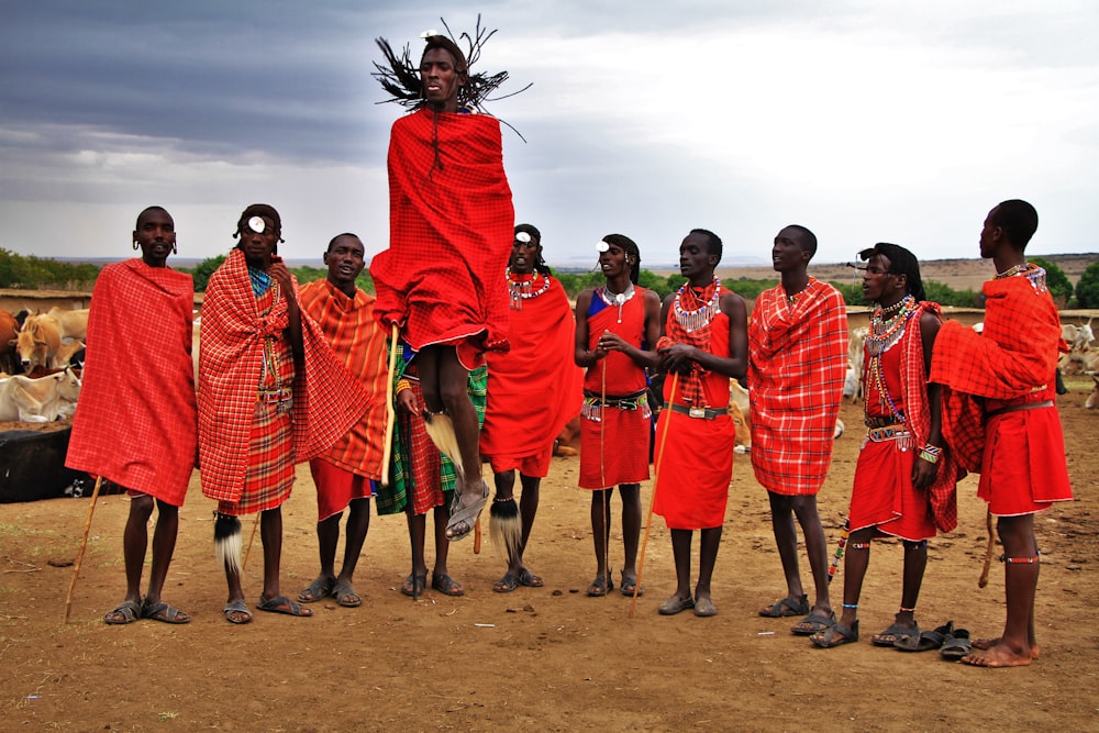 grupo de hombres vestidos con trajes rojos de pie sobre suelo marrón