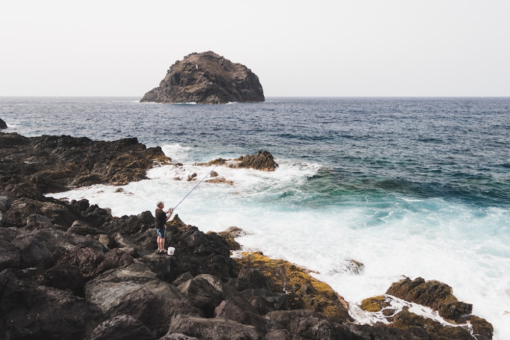 man fishing on seashore during daytime