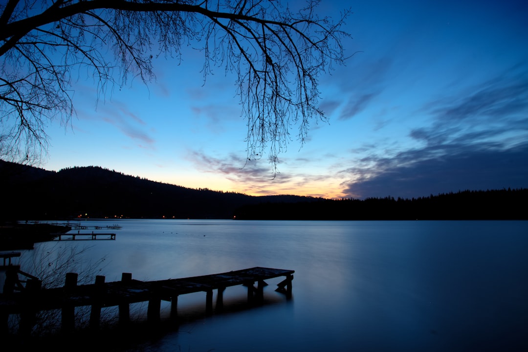 silhouette of dock near body of water during golden hour