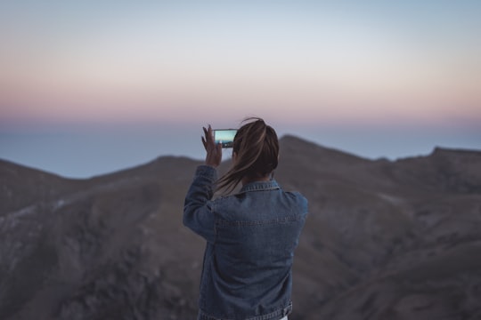 woman in blue denim jacket taking picture of mountain in Kalavrita Greece