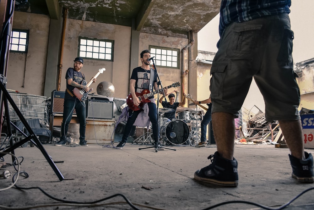 man singing with band mates on gray concrete room