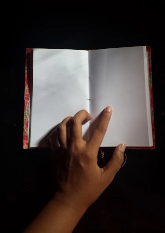 A close-up of hands flipping through crisp, blank pages in a well-lit room.