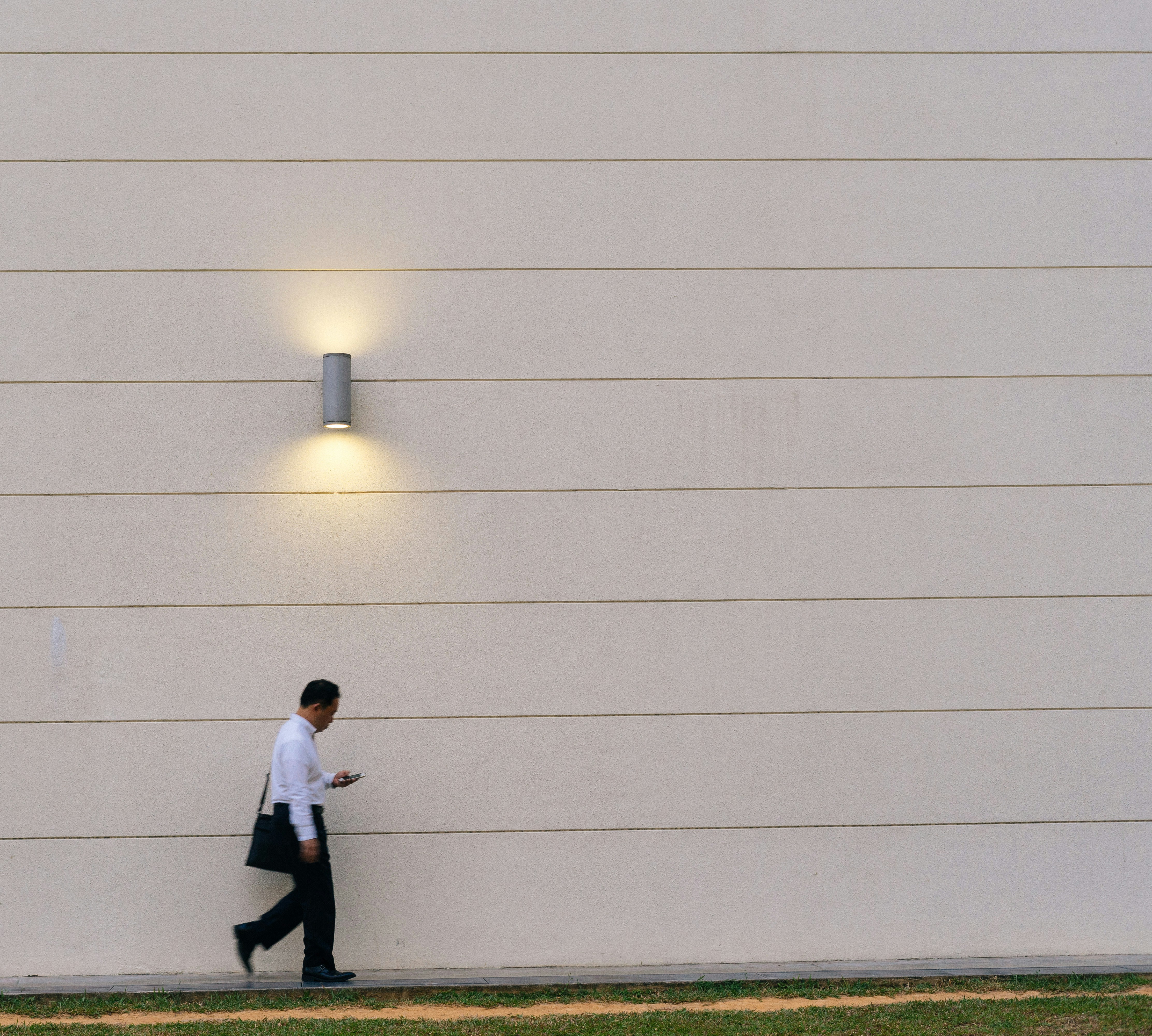 It was a fine afternon when I see a man passed by the wall. I accidentaly snap a picture where the lamp just below the man.