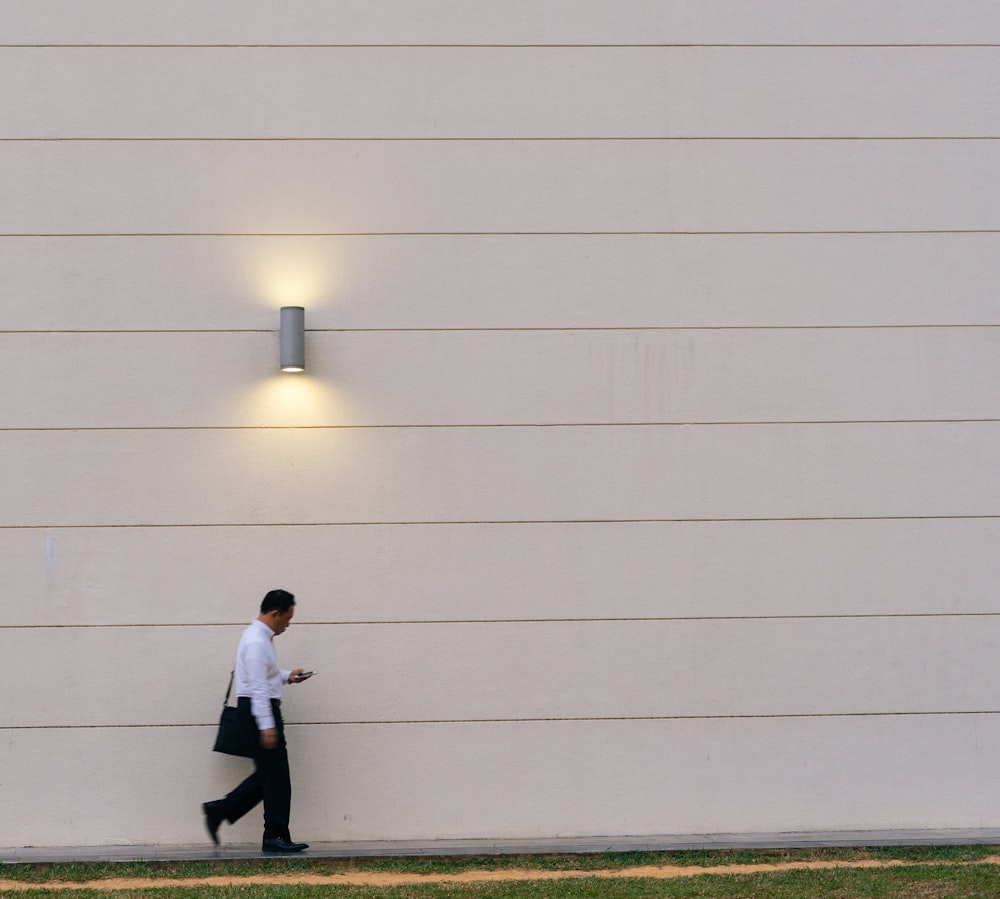 man in white shirt and black pants standing on gray concrete floor