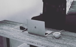 Cozy, monochrome desk setup with coffee, notebook, and sleek digital graphics.