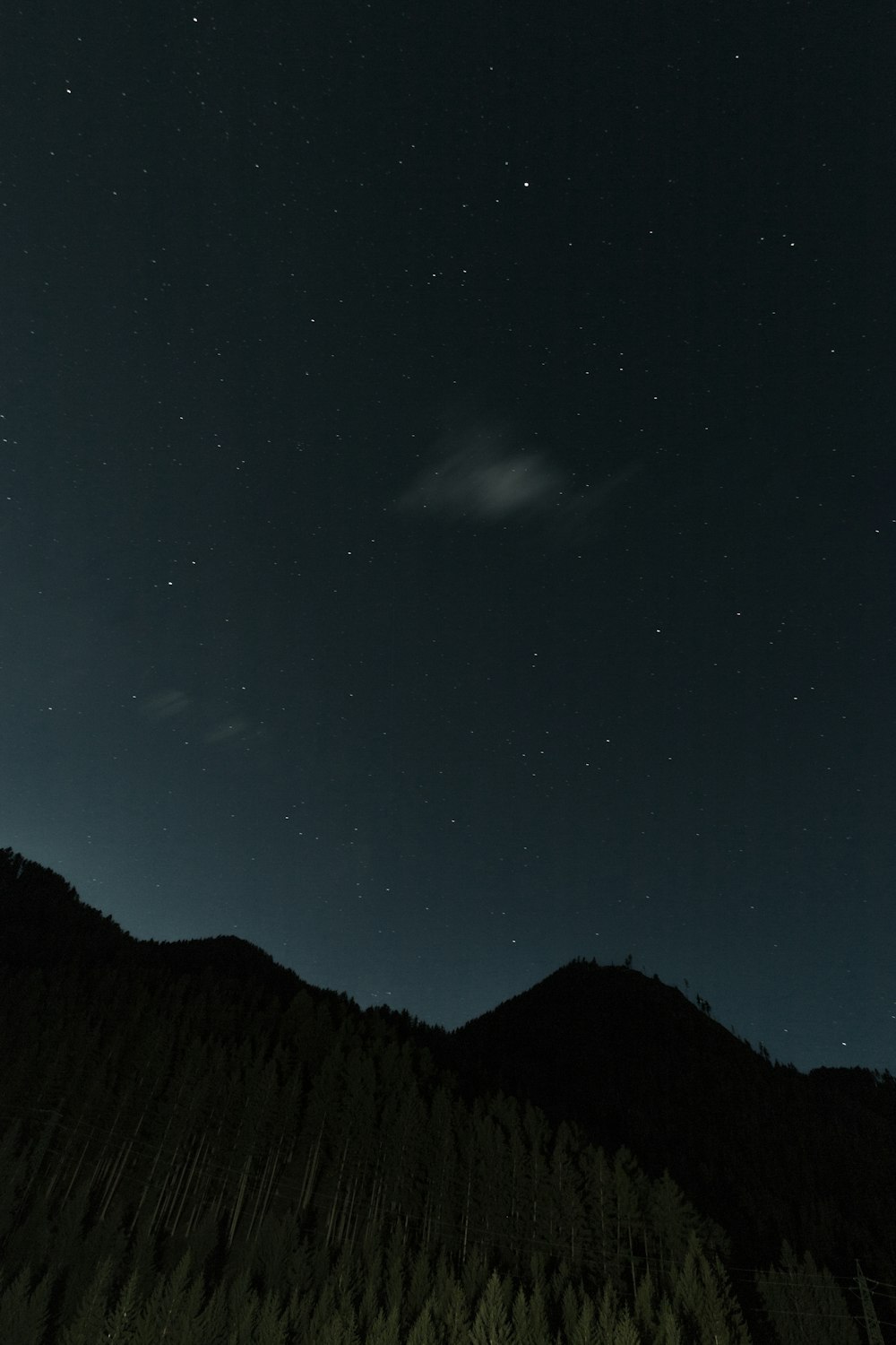 silhouette of mountain under gray sky at night