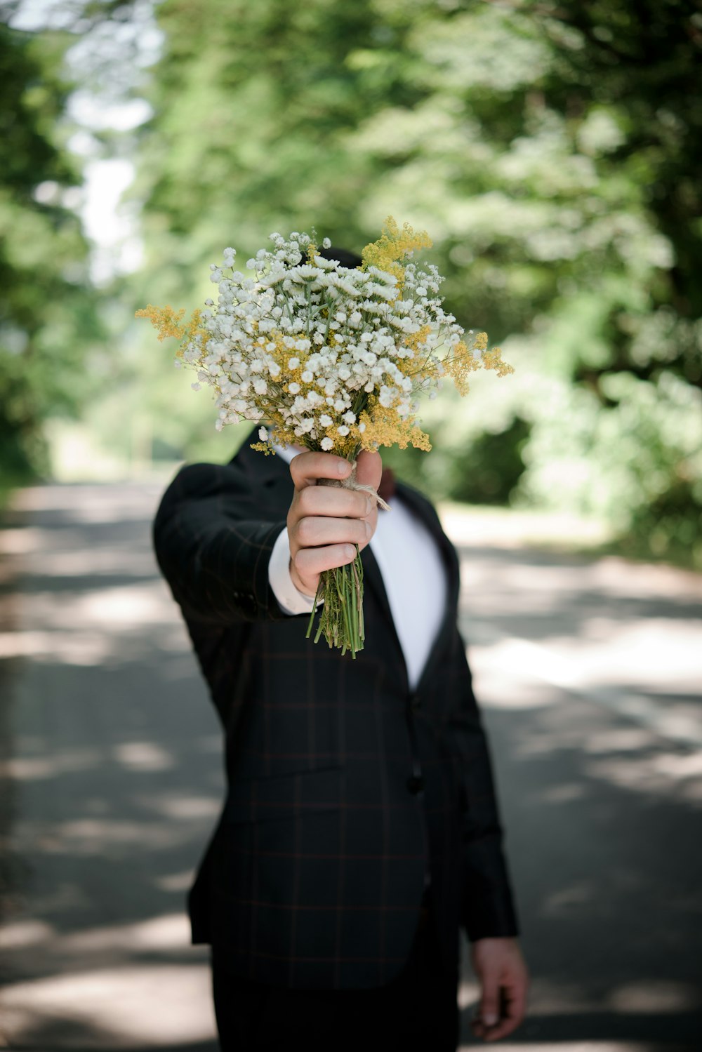 花束を持った黒いスーツのジャケットを着た男性のセレクティブフォーカス写真