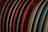 A series of plates are arranged vertically and closely together. The plates are of different colors, including red, blue, and beige, and they are placed in a drying rack or storage setting.