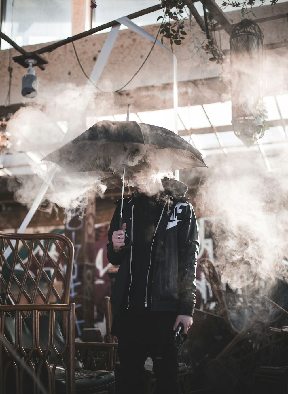 homem segurando um guarda-chuva preto cobrindo-o de fumaça