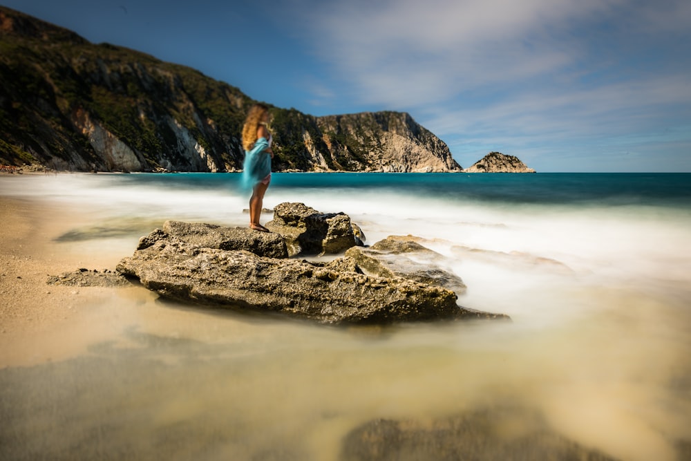 woman standing on rock at beach during daytime