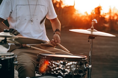 person playing drum during golden hour drumstick teams background