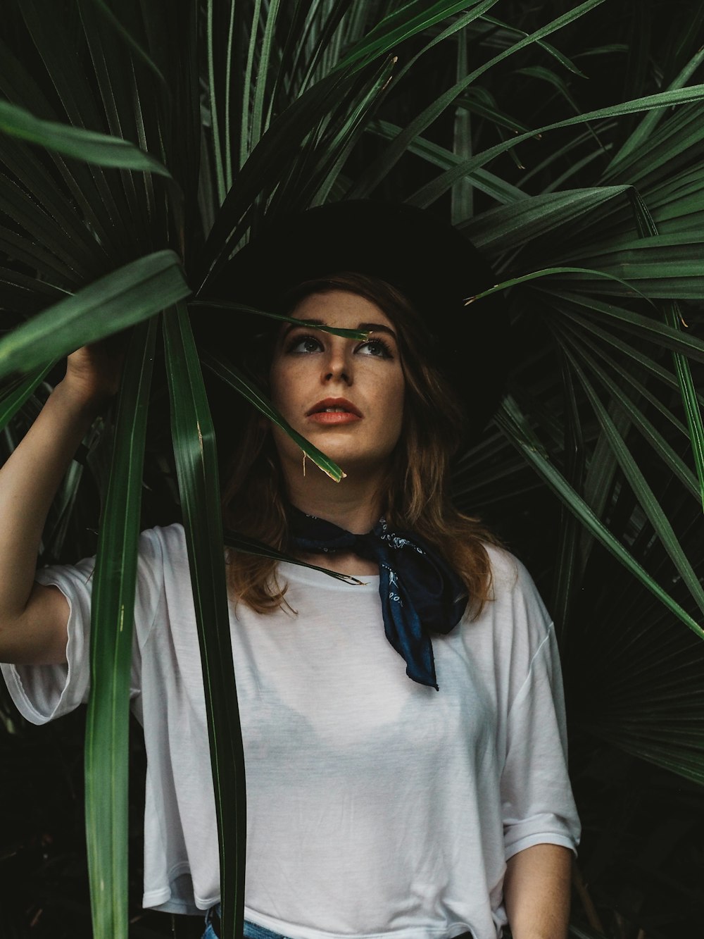 Mujer con blusa blanca de cuello redondo sosteniendo la planta