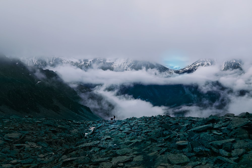 Persona de pie en la cima de la montaña rodeada por un mar de nubes