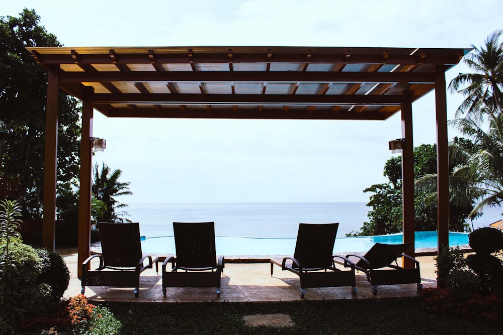 foto de quatro espreguiçadeiras sob gazebo de frente para piscina