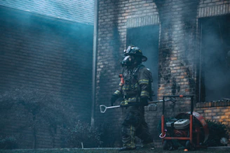 Technician in protective gear carefully restoring a fire-damaged home interior with specialized equipment.