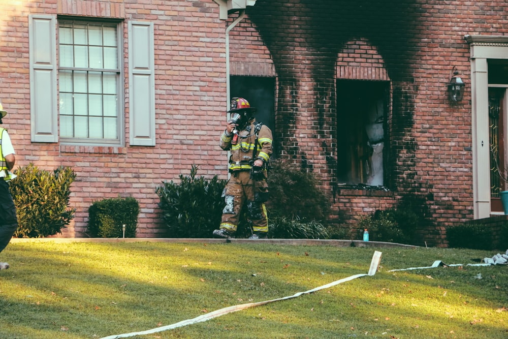 Bombero caminando frente a la casa de ladrillos marrones