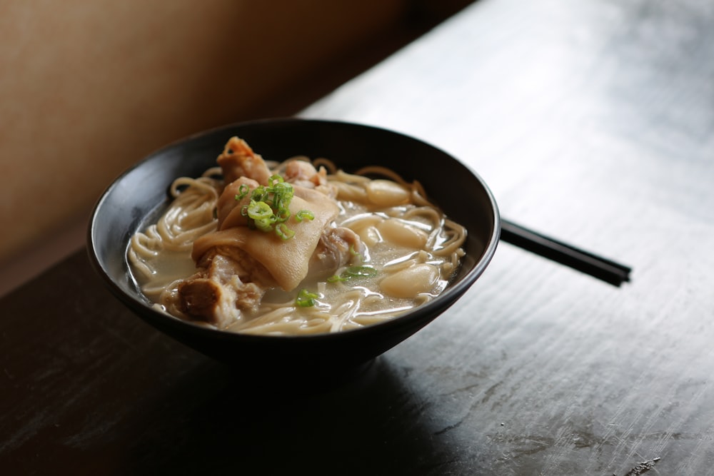 テーブルの上の黒いお椀に盛り付けられた麺