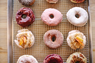An assortment of colorful doughnuts arranged on a rustic wooden table, showcasing various flavors and toppings.