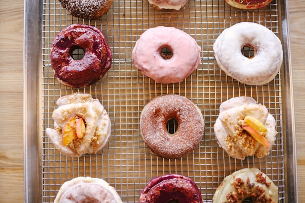 An assortment of colorful doughnuts arranged on a rustic wooden table, showcasing various flavors and toppings.