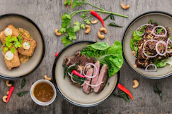 three plates of asian food on wood table