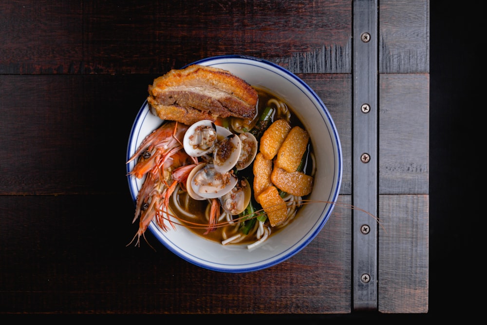 a bowl of soup with shrimp, mussels and bread