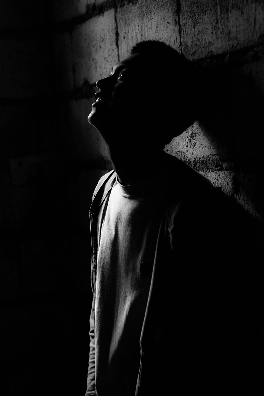 grayscale photography of man leaning on wall