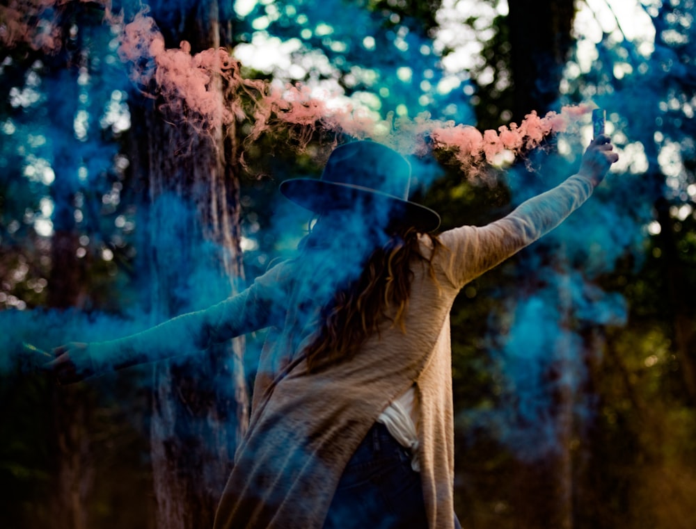 mulher em bege de manga comprida top segurando dois flares de cor rosa e azul durante o dia