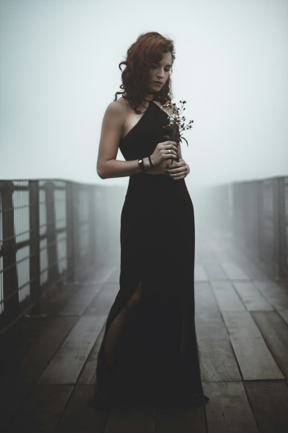 woman standing in the bridge while holding flowers