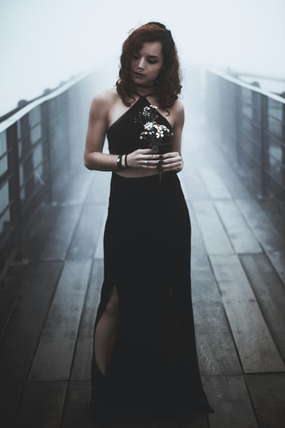 woman standing in the bridge while holding flowers