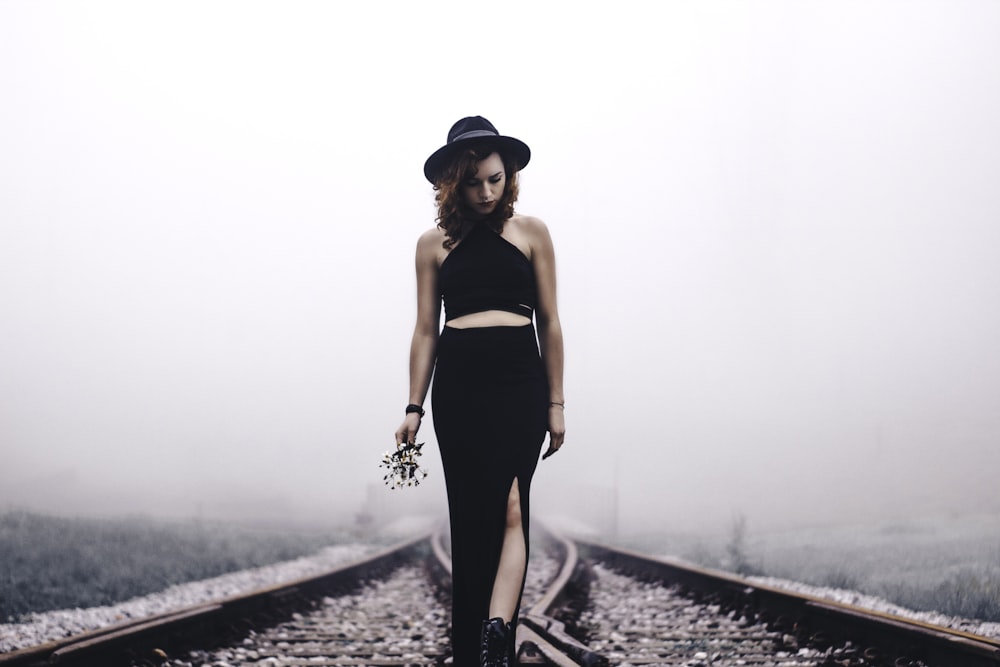 Mujer sosteniendo flores mirando en los rieles del tren