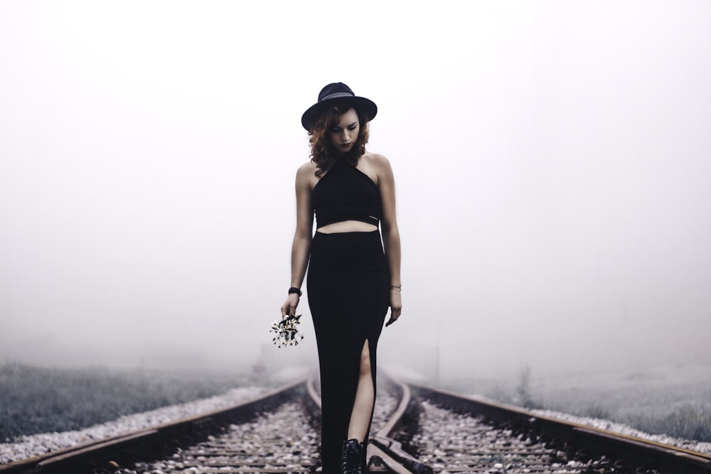 woman holding flowers looking on train rails