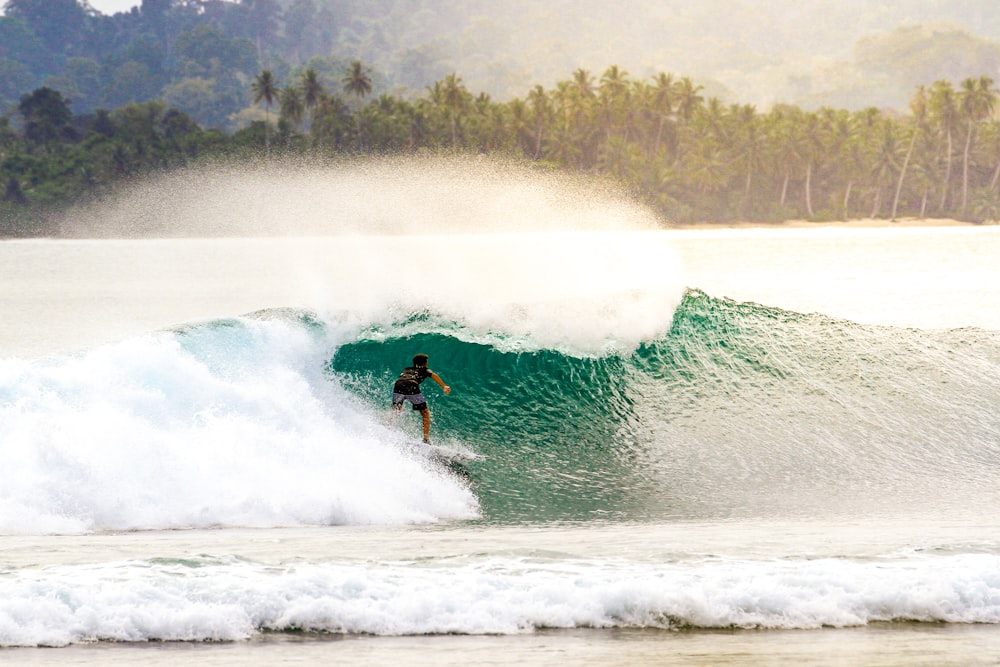 Persona che fa surf su un'onda enorme durante il giorno