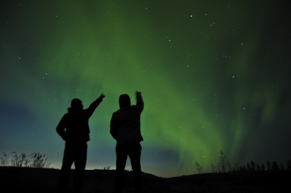 silhouette photo of two person looking up the sky