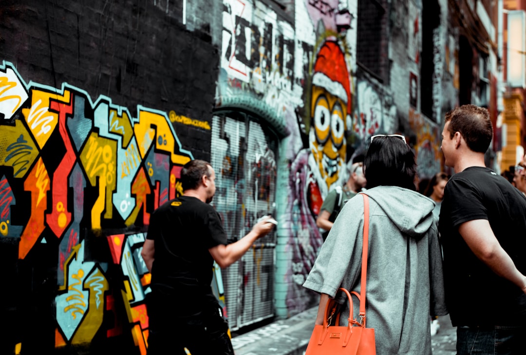 man drawing graffiti, Passers by stop to talk to a local street artist who is giving away free canvases (we took one hom