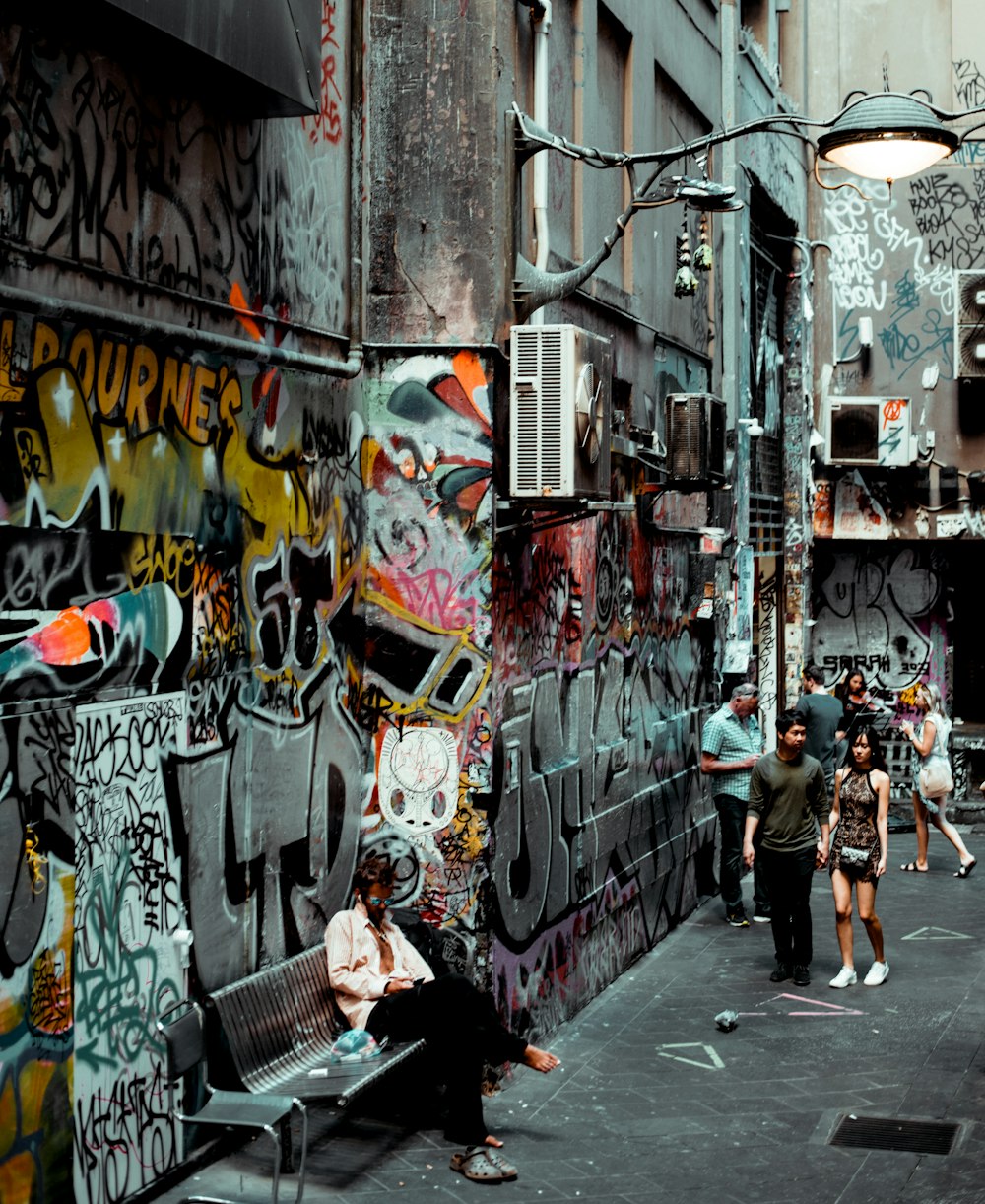 people walking beside wall with graffitis