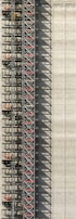 An industrial structure with a scaffolding system against a large concrete wall. The scaffolding features metal beams, platforms, and red sections, casting intricate shadows onto the wall. The concrete surface is smooth with subtle vertical lines.