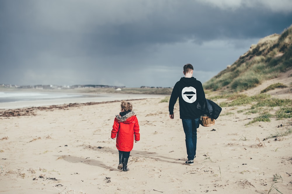 man and girl walking on beach