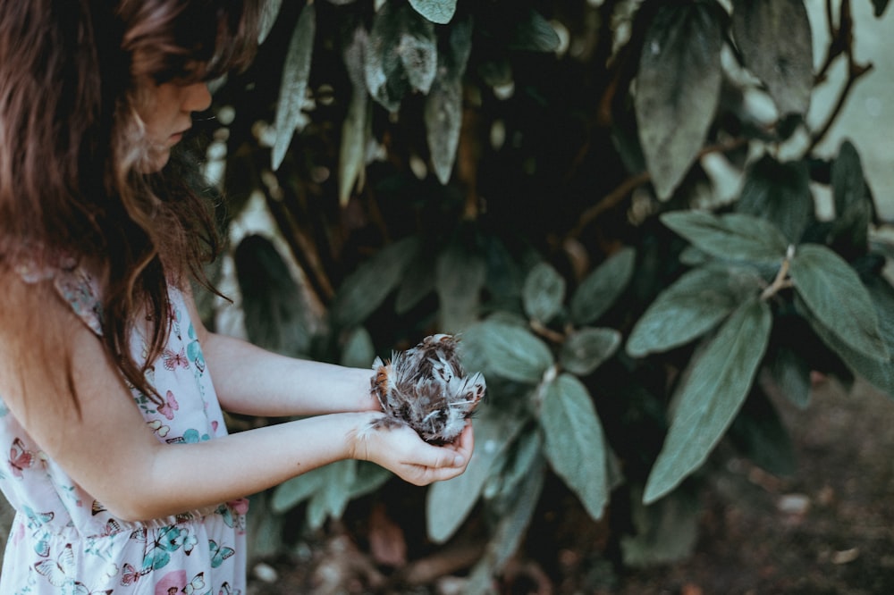 girl carrying kitten nearby tree