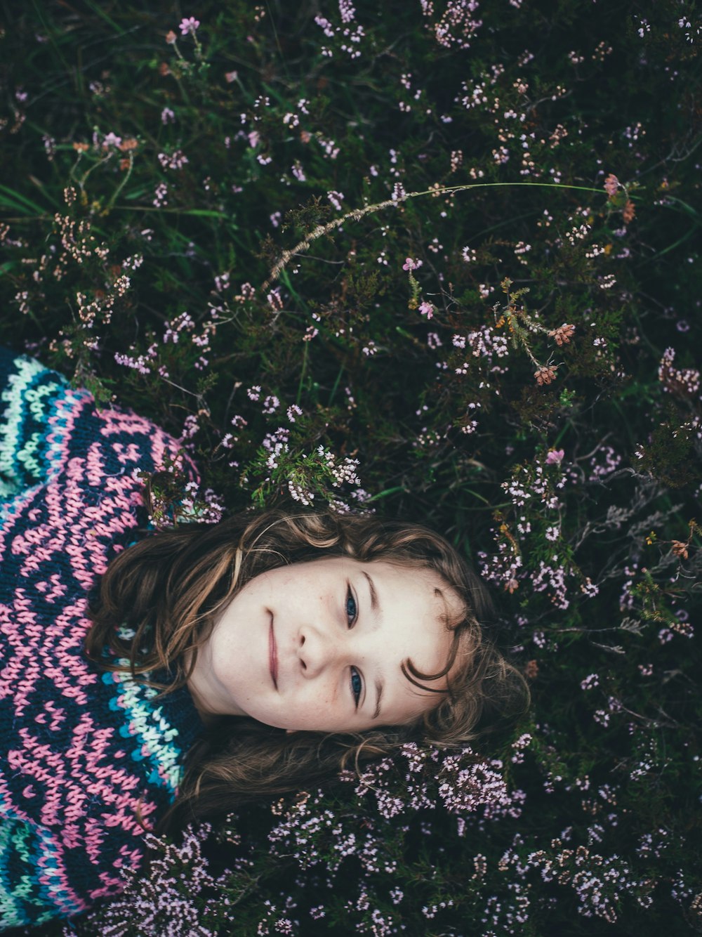 menina deitada em flores de pétalas cor-de-rosa