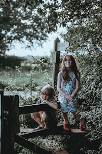 photo of two boy and girl sitting on bench