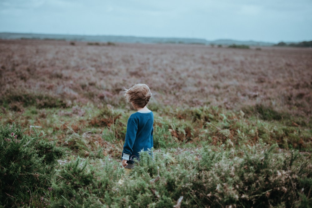 girl standing in the middle of plains during daytime
