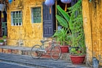 green bicycle parked beside yellow concrete house at daytime