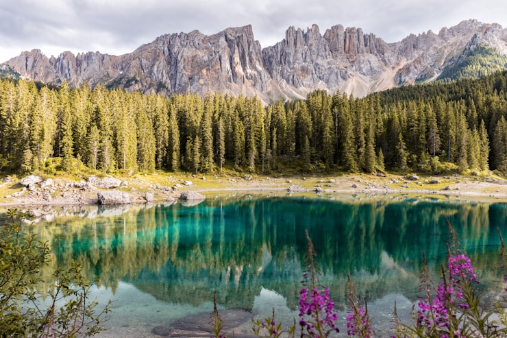 It was a cloudy day and I was on my couch, bored because I was doing nothing, so at 4pm I decided to go to Lake Carezza. The weather was not good, but according to the forecast it would be better for the sunset. It was worth it.
Legend has it that a magician smashed the rainbow he had created to seduce a mermaid into the lake, sending beautiful colors tumbling into the water. In truth, many of the beautiful colors are reflected from the surrounding evergreen forests, colors of the mountain rock faces, and the sky above.