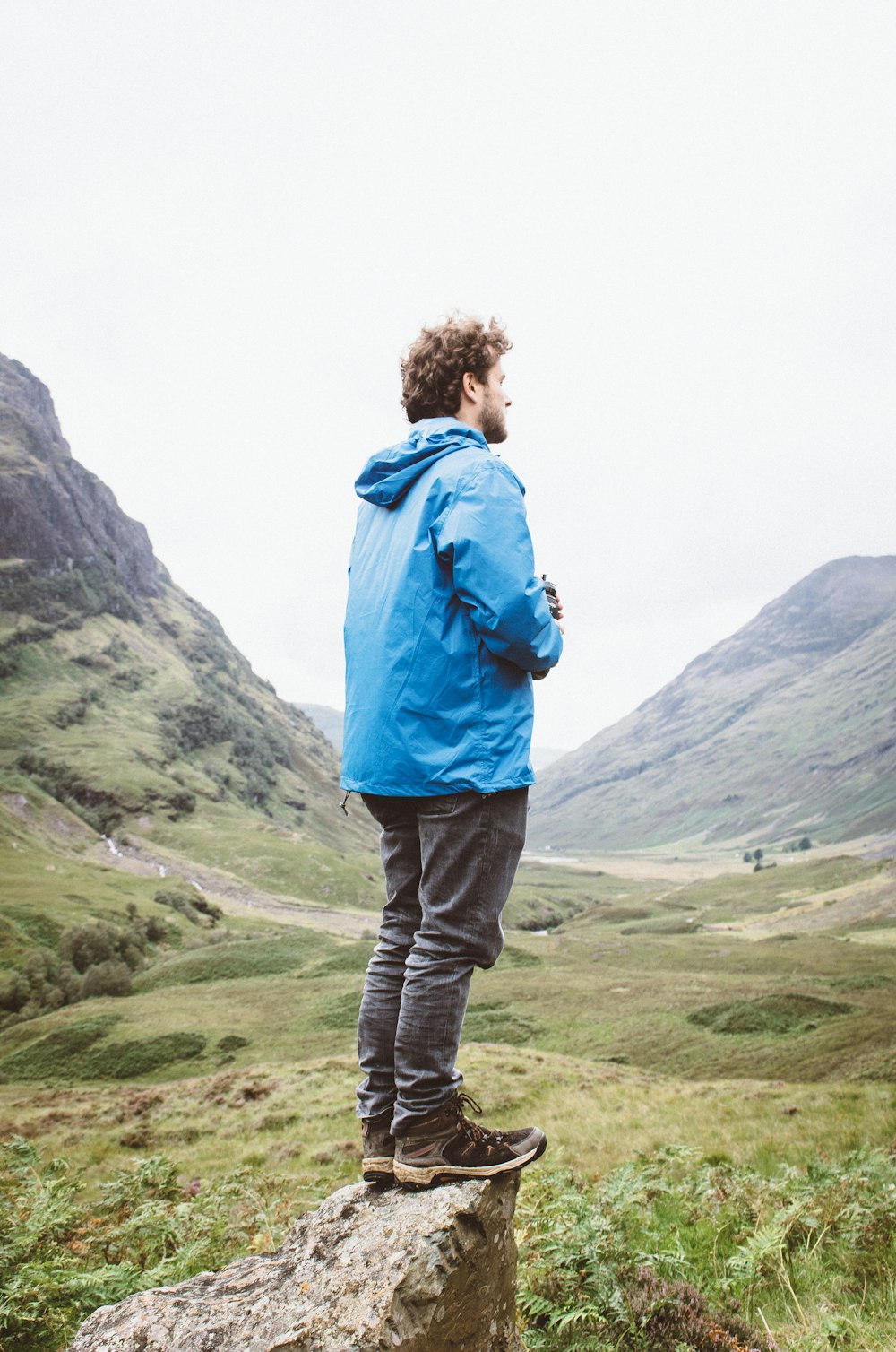 man standing on rock looking through mountain