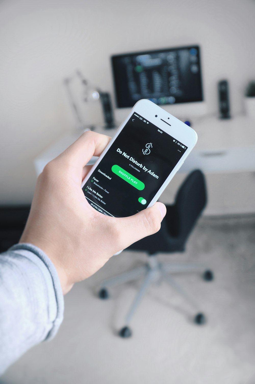 person holding iPhone showing Spotify application