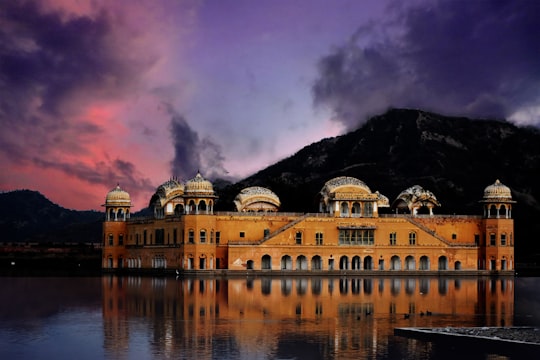 orange wall paint building near on mountain and body of water photo in Jal Mahal India