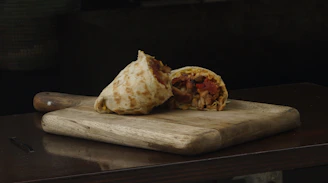 Close-up of a freshly wrapped burrito bursting with vibrant ingredients on a rustic wooden table.