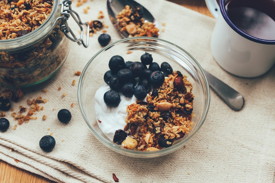 Granola, blueberries, and yogurt in a glass bowl
