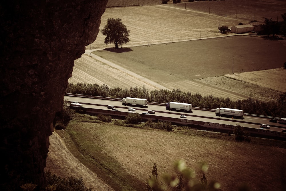 trail photography of running vehicles on street between grass field