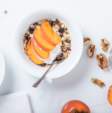 bowl of cereal with sliced fruits and spoon